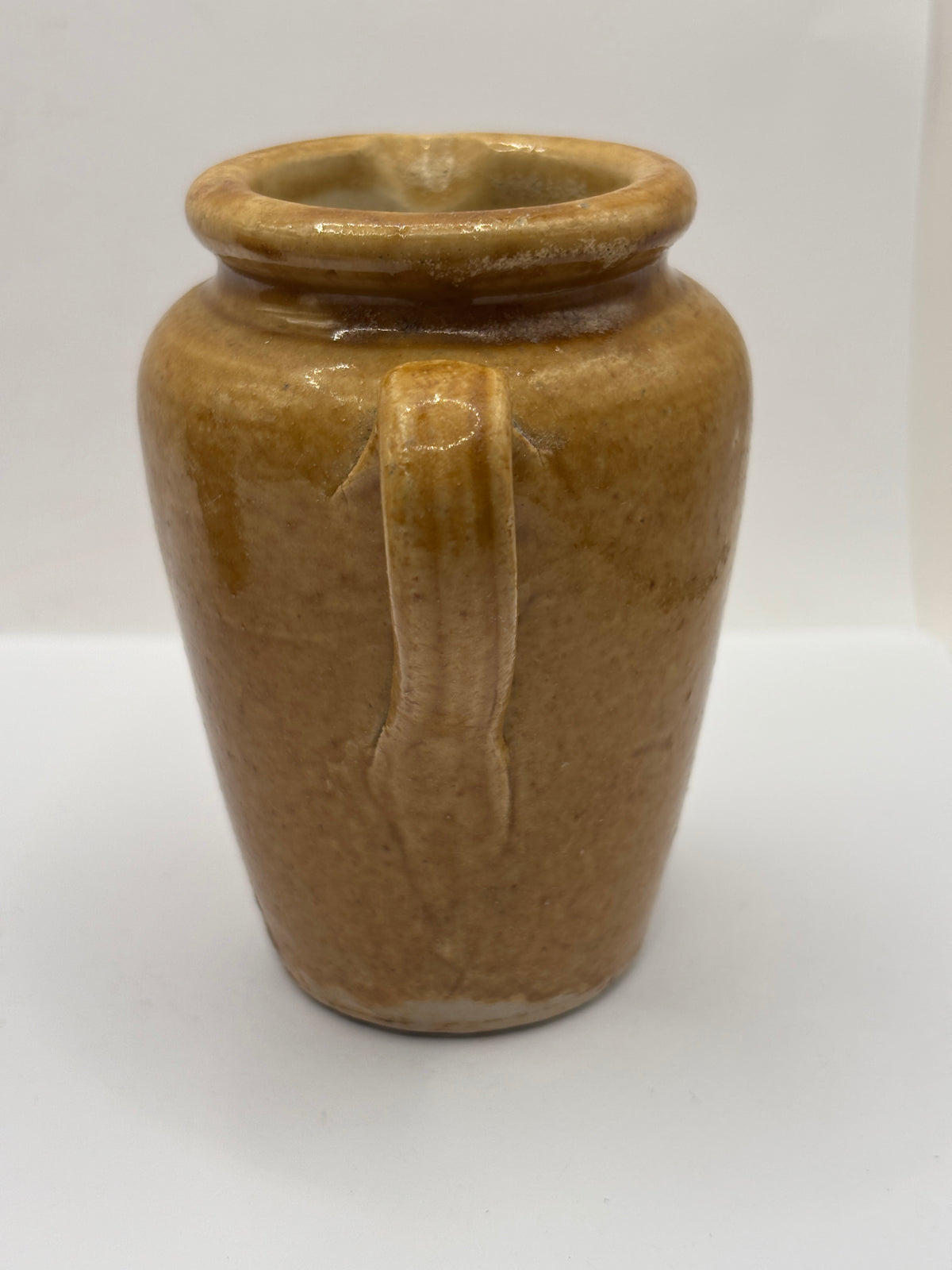 Old brown stoneware cream pot, pouring cream