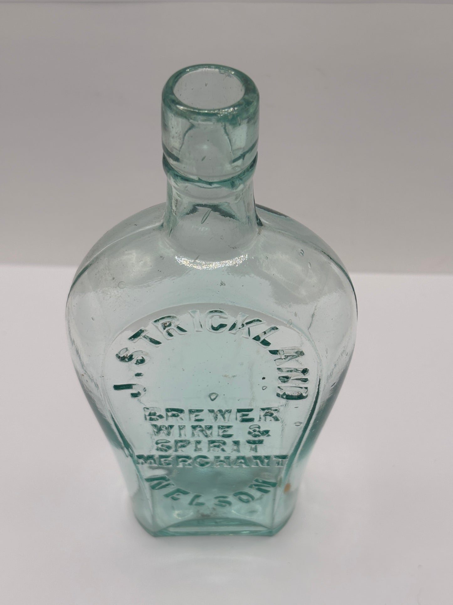 Old glass spirit flask, J.Strickland brewer wine & spirit merchant. Nelson