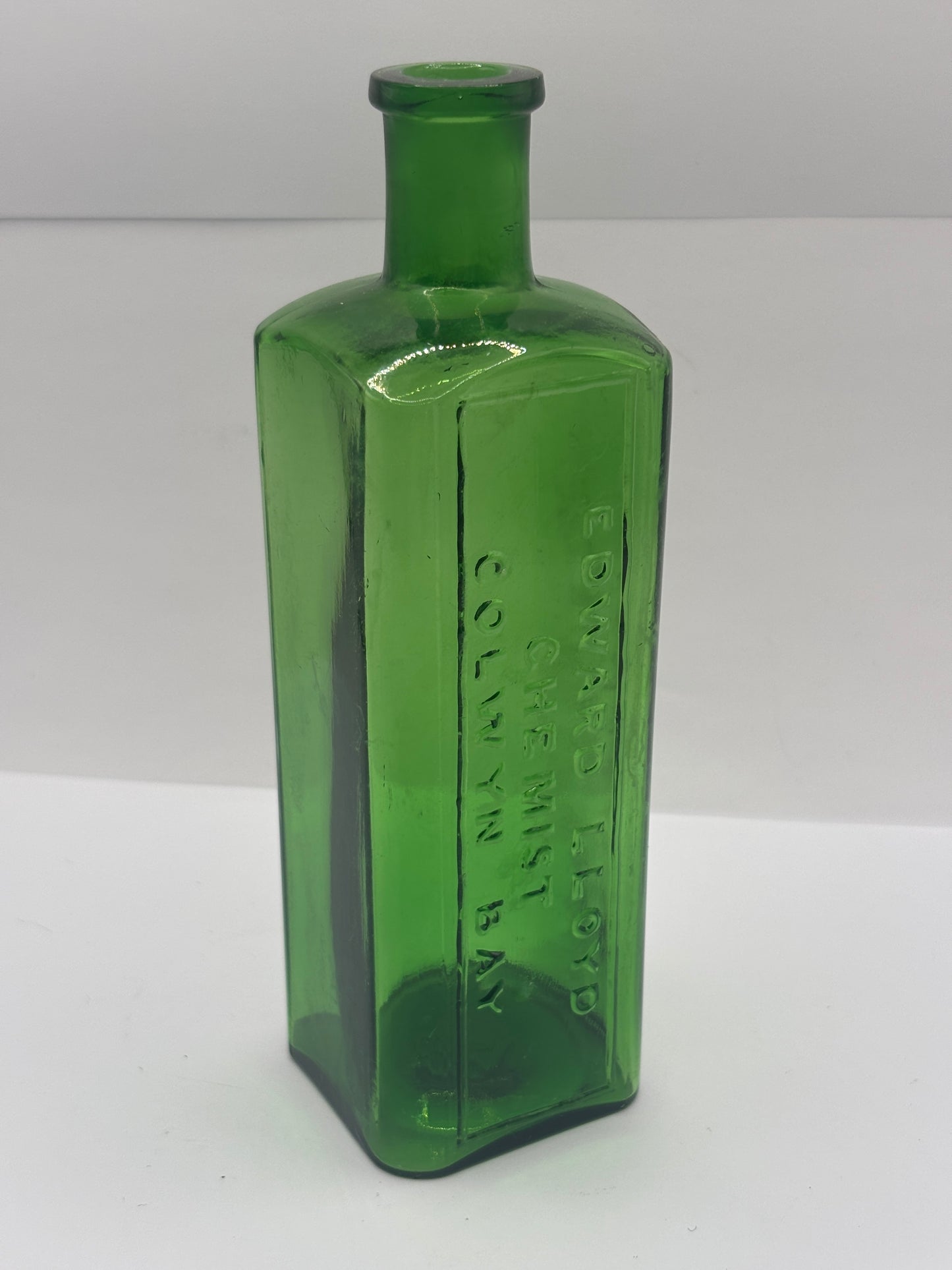 Old green glass advertising chemist bottle. Edward Lloyd chemist Colwyn bay