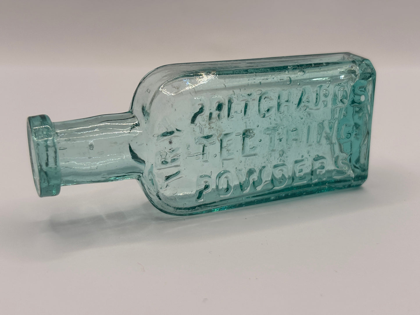 Old small aqua glass advertising bottle. Pritchards teething powders