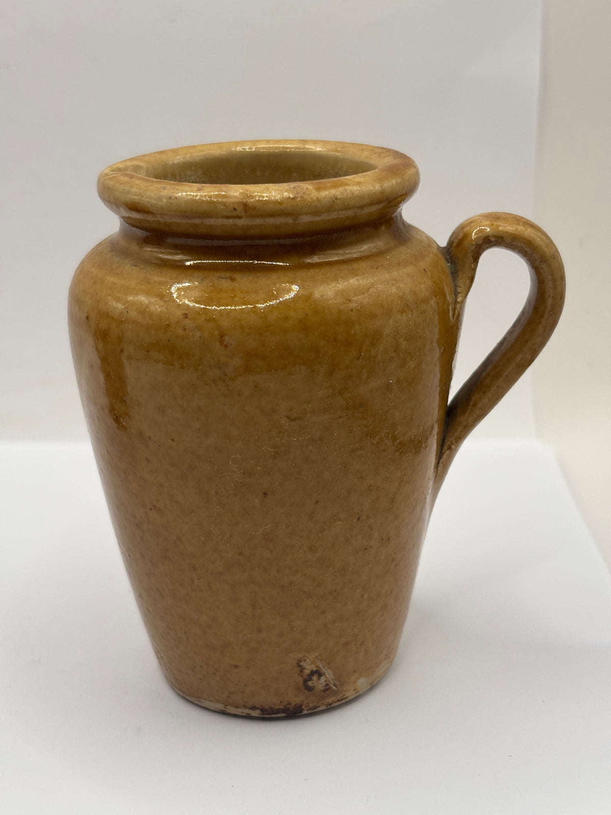 Old brown stoneware cream pot, pouring cream