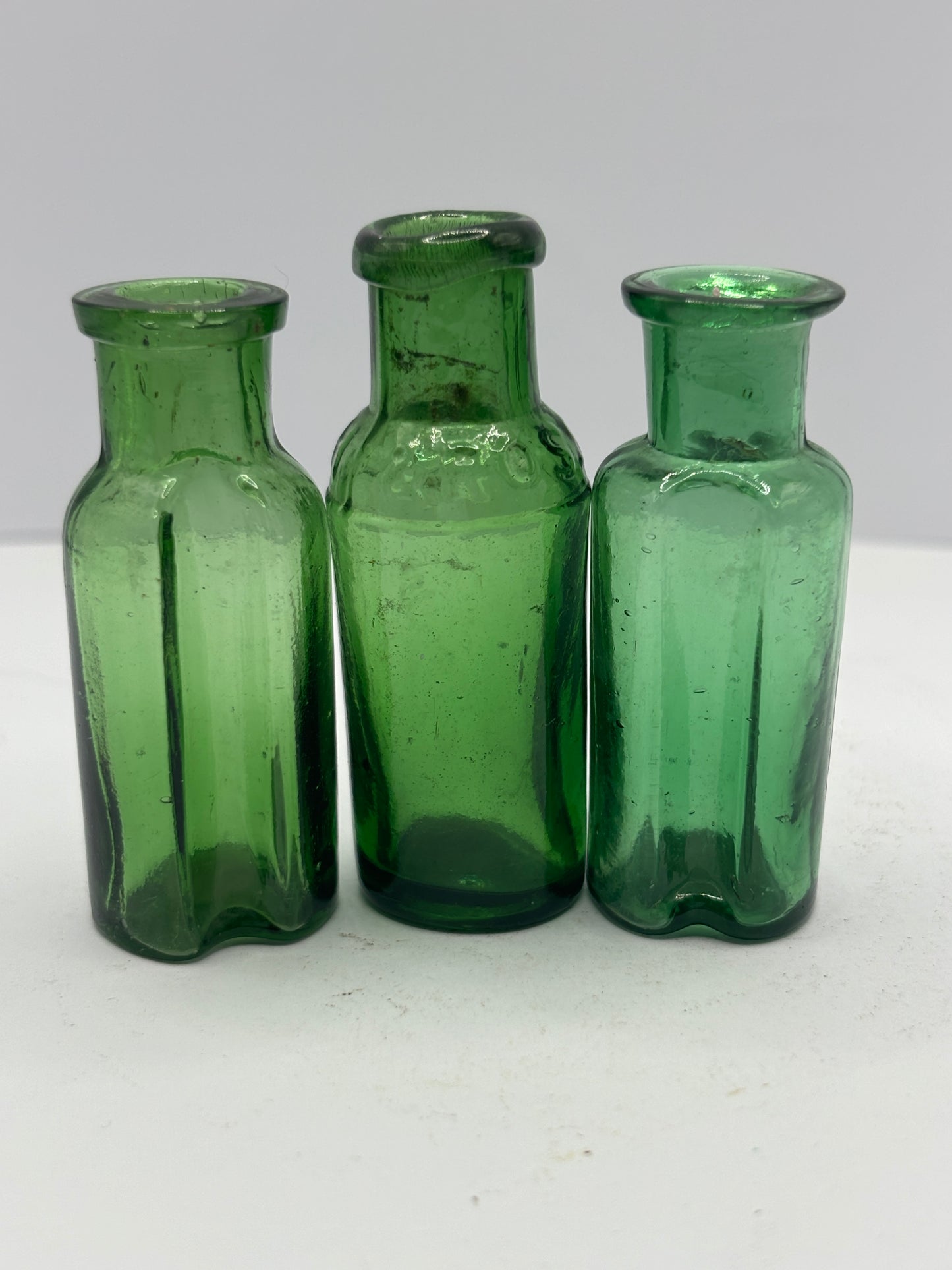 3 small green glass bottles