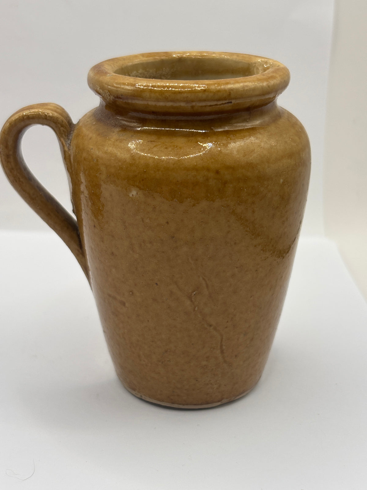 Old brown stoneware cream pot, pouring cream