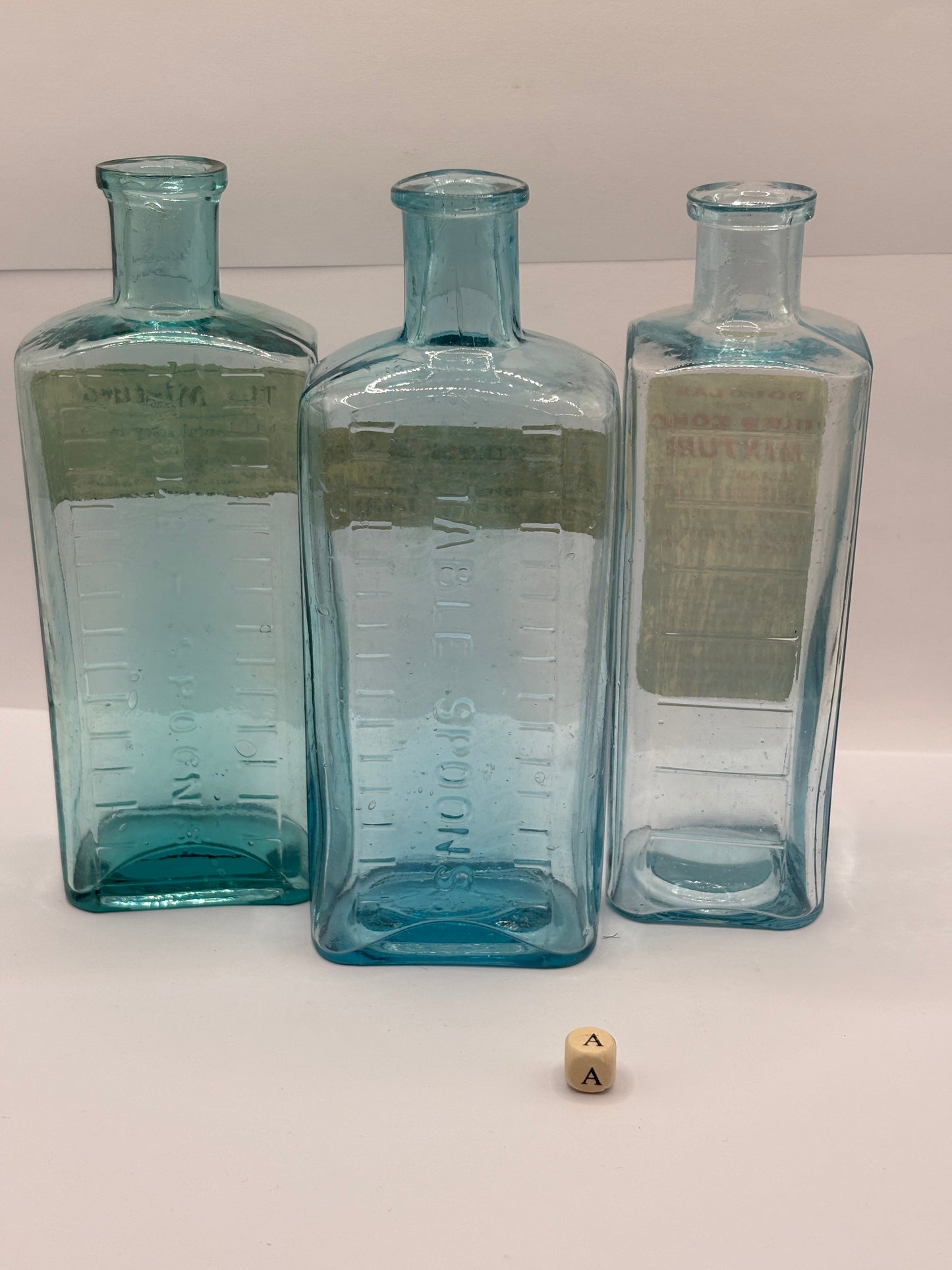 3 old glass chemist bottles with added labels (a)
