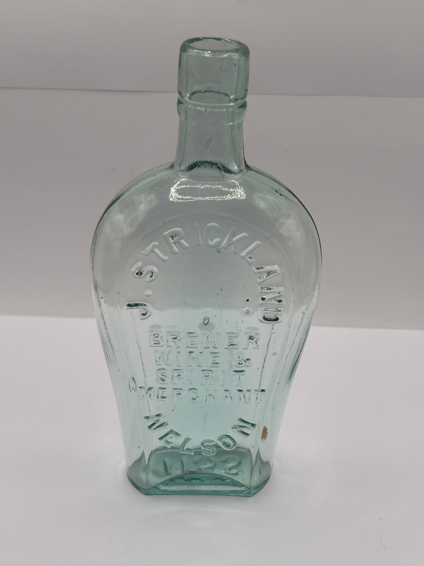 Old glass spirit flask, J.Strickland brewer wine & spirit merchant. Nelson