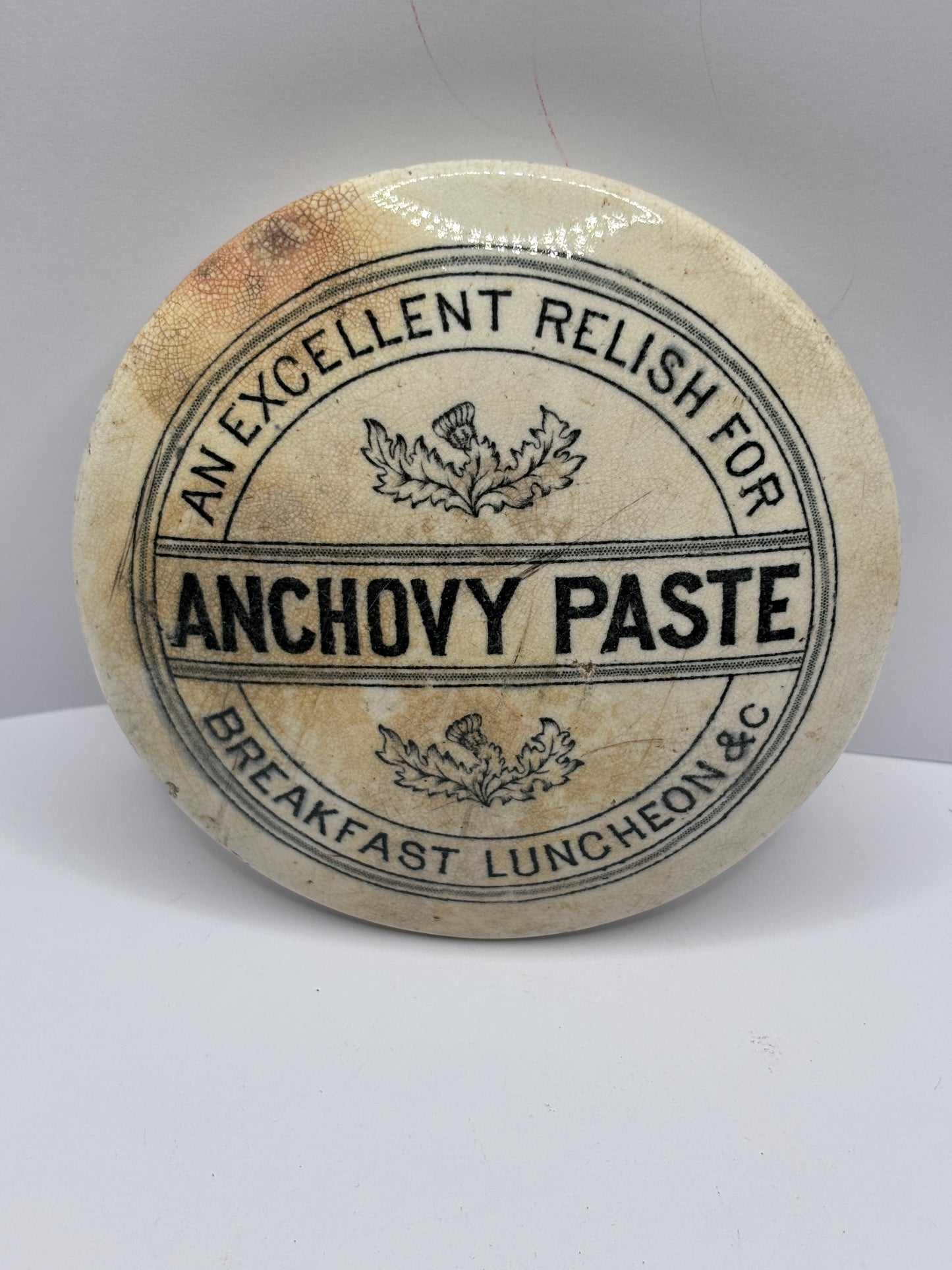 Old anchovy paste advertising pot lid, stained & crazed