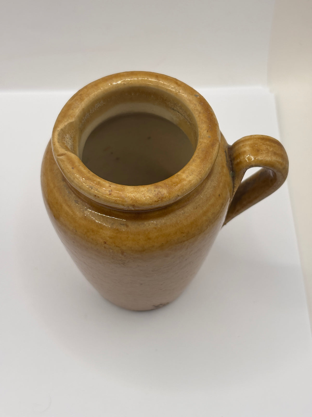 Old brown stoneware cream pot, pouring cream