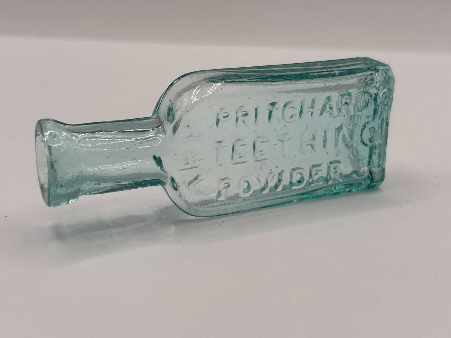 Old small aqua glass advertising bottle. Pritchards teething powders