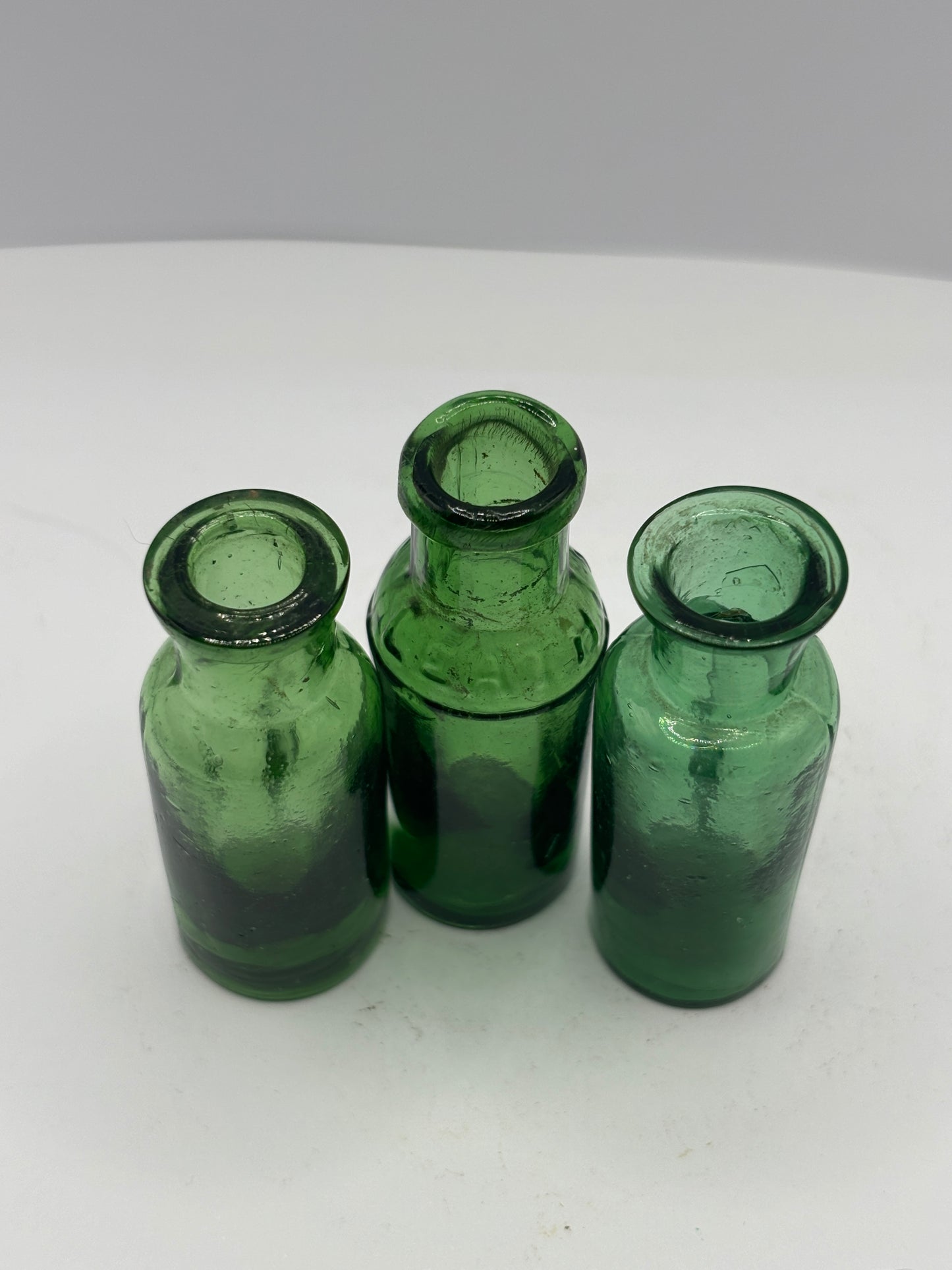 3 small green glass bottles