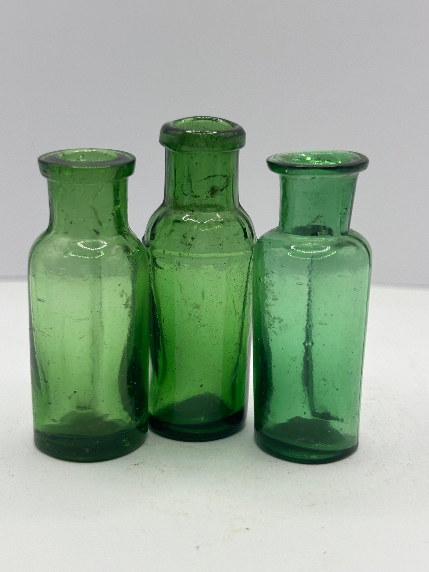 3 small green glass bottles